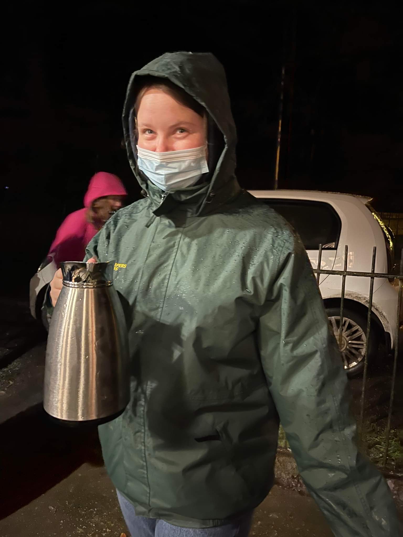 a girl wearing a hooded coat and carrying a jug